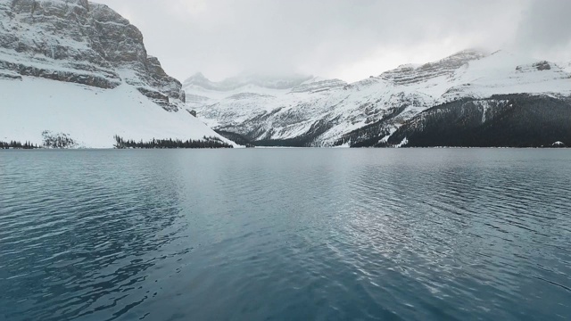 在加拿大阿尔伯塔省，无人机视频飞过被雪白的岩石包围的弓湖表面视频素材