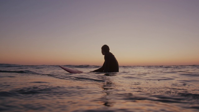 一个年轻人在日落时冲浪视频素材