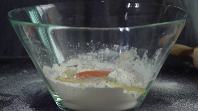 慢动作将蛋黄与面粉一起倒入玻璃碗中。烹饪生面团，自制面包烘焙概念视频素材