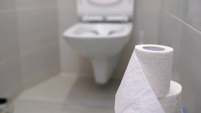 卫生间现代化的房间里有一个柜台下的白色马桶，厕纸映衬着马桶的背景视频下载