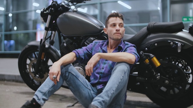 年轻有魅力的男子在夜晚的街道上骑摩托车。摩托车手与定制摩托车视频下载