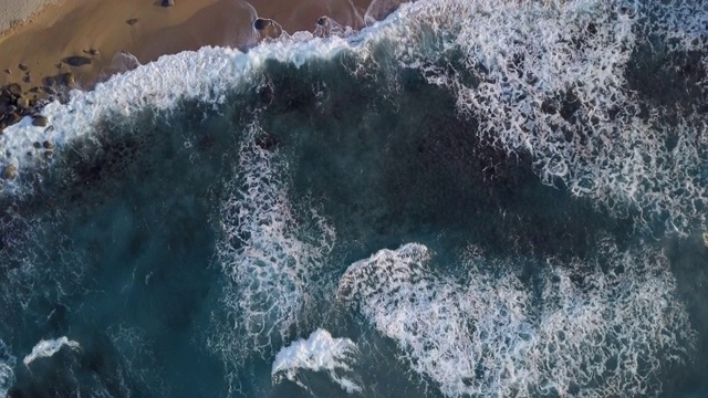 旋转图像海浪拍打海岸和白色气泡停留在美丽的蓝色海洋表面。视频素材
