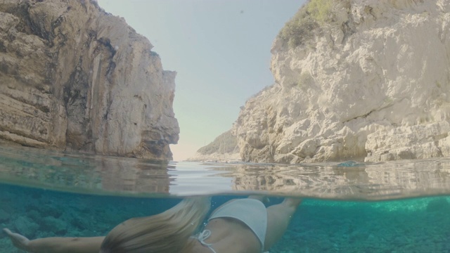 一名身穿比基尼的年轻女子在克罗地亚的亚得里亚海水下游泳视频素材