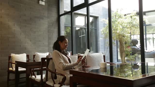 优雅成熟的女性在咖啡店使用数字平板电脑，高清视频素材