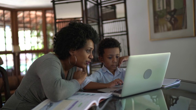 母亲帮助儿子在笔记本电脑上学习视频素材