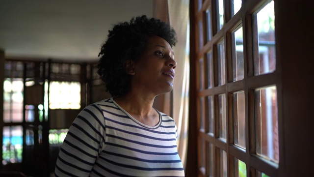 成熟的女人透过窗户在家沉思和思考视频素材