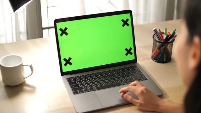 女人看着空白绿色屏幕的笔记本电脑视频素材