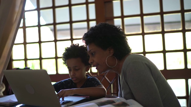 母亲帮助儿子在笔记本电脑上学习视频素材