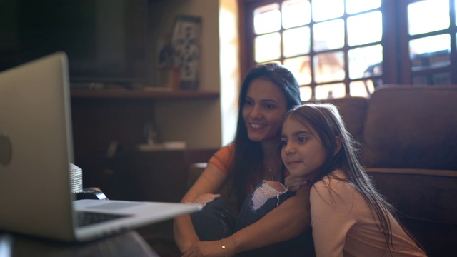 母亲和女儿在家里用笔记本电脑看电影或视频视频下载