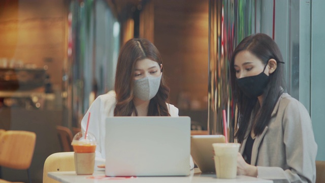 两个女商人戴着口罩开会讨论商业计划视频素材