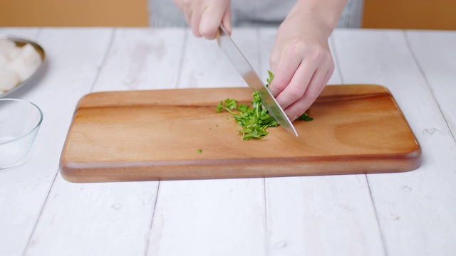 切欧芹的特写镜头，在木板上切绿叶，4k。女人的手的概念是用厨师刀切蔬菜。视频下载