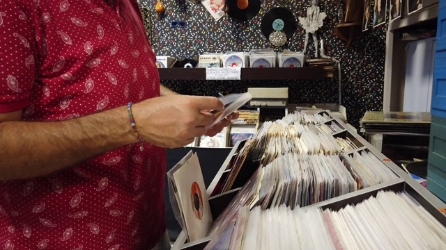 一个年轻人正在唱片店看旧唱片视频下载