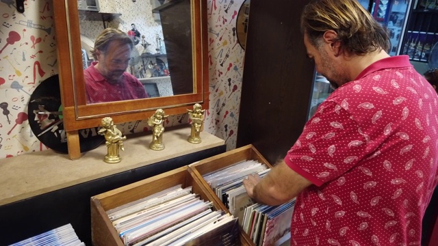 一个年轻人正在唱片店看旧唱片视频素材