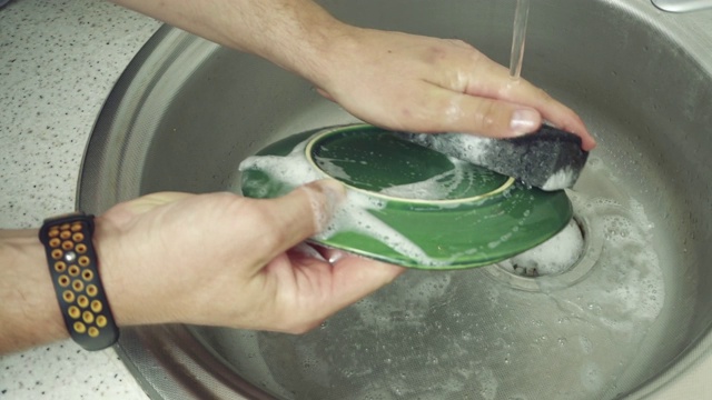 男人在厨房水槽里洗盘子的特写镜头。视频下载