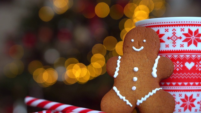 圣诞视频与姜饼人红色马克杯与圣诞装饰轻米粉从圣诞树和红色条纹假日糖果。圣诞糖果和杯与棉花糖在木材背景。4 k的视频视频素材