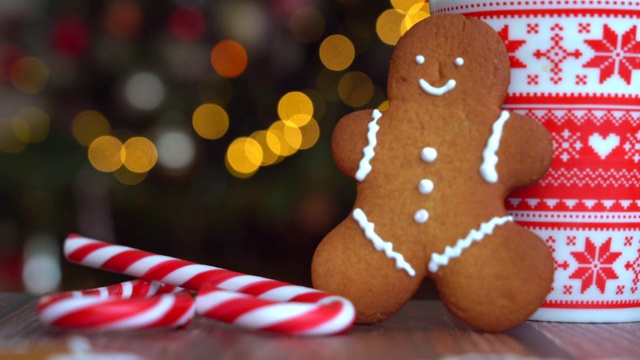 圣诞视频与姜饼人红色马克杯与圣诞装饰轻米粉从圣诞树和红色条纹假日糖果。圣诞糖果和杯与棉花糖在木材背景。4 k的视频视频素材