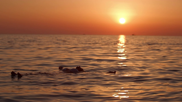 克罗地亚亚得里亚海，日落时分，一名年轻女子在平静的海面上漂浮视频素材