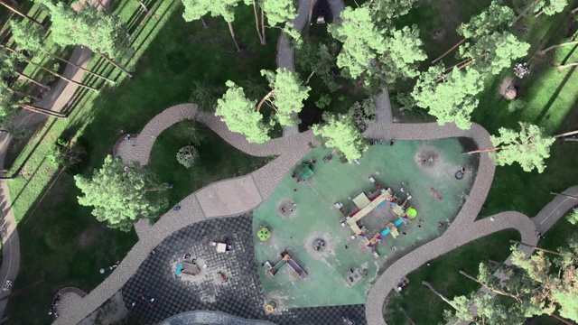 操场与秋千周围的绿色松树和草坪在城市公园在阳光明媚的一天，顶部无人机视图视频下载