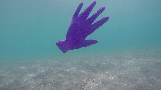 橡胶手套漂浮在海面上。西班牙阿尔梅里亚。视频下载