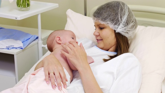 慈爱的母亲在诊所的医疗沙发上爱抚新生儿视频下载