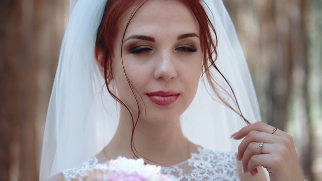 一个新娘在森林里的肖像，穿着一件婚纱，触动了她的一缕头发，特写，慢动作视频下载