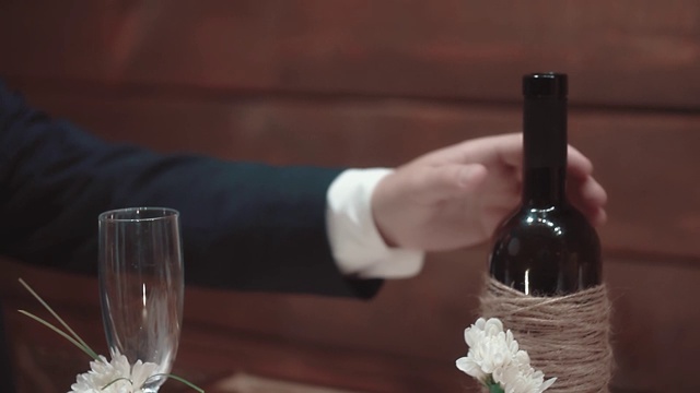 一个年轻人从餐馆的桌子上拿起一瓶葡萄酒，特写，慢镜头视频素材