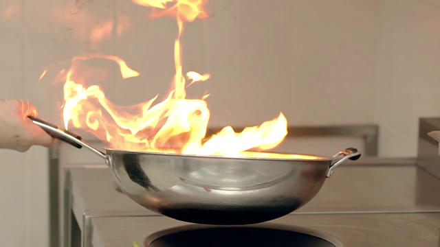 厨师在燃烧的煎锅上准备蔬菜。视频下载
