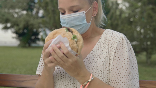 SLO MO女人通过一个保护面具表现出对汉堡的兴奋视频素材