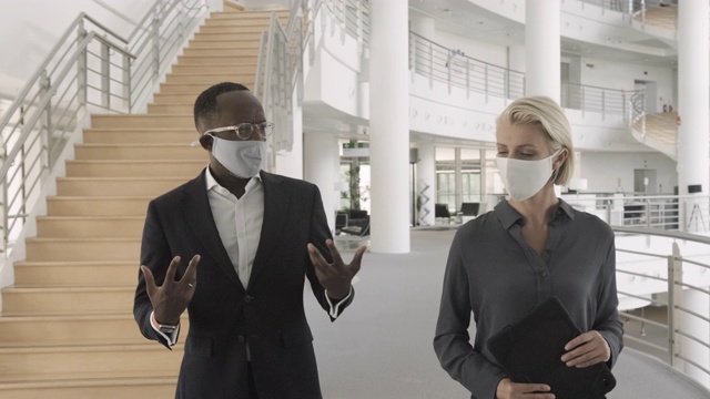商务人士戴着口罩在现代企业办公大厅开会和散步视频素材