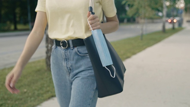 SLO MO一名年轻女子在街上行走时挂在钱包上的防护面罩视频素材