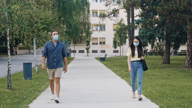 一对戴着防护面罩的年轻夫妇在公园里散步视频素材