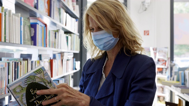 戴面具的妇女在书店看书视频素材