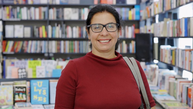 一个快乐成熟的女人在书店的肖像。视频素材