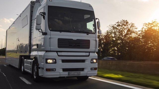 在高速公路上行驶的带有拖车的货运卡车。白色卡车在清晨运送货物视频素材