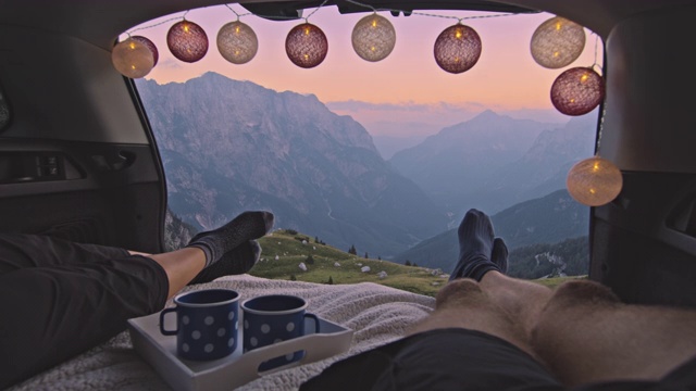 SLO MO露营夫妇休息和享受山中的日落从汽车后备箱视频素材