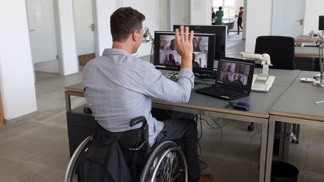 一个坐在轮椅上的残疾人在他的办公桌前召开视频会议视频下载