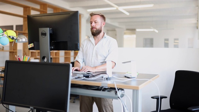 男人工作在符合人体工程学的站立办公桌在办公室视频下载