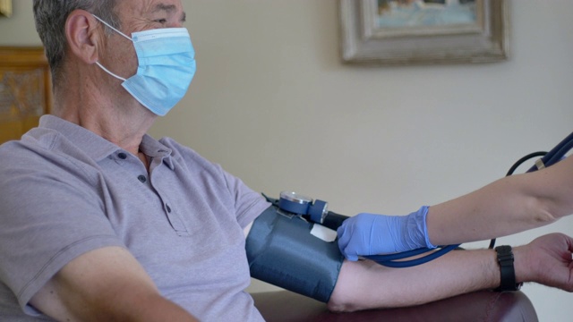 女护士用血压计测量老年男性病人的血压视频下载