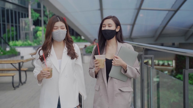 两个亚洲女商人拿着咖啡杯边走边谈生意视频素材
