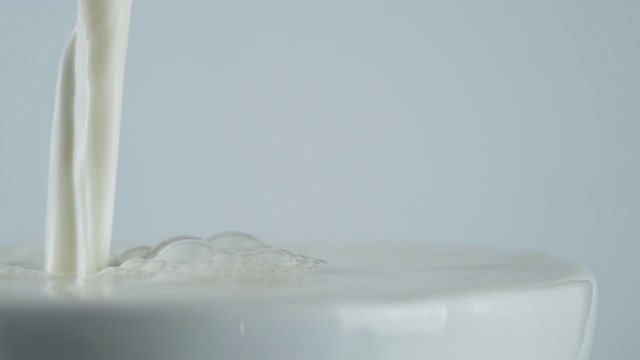 牛奶从杯沿倒进玻璃杯。视频素材