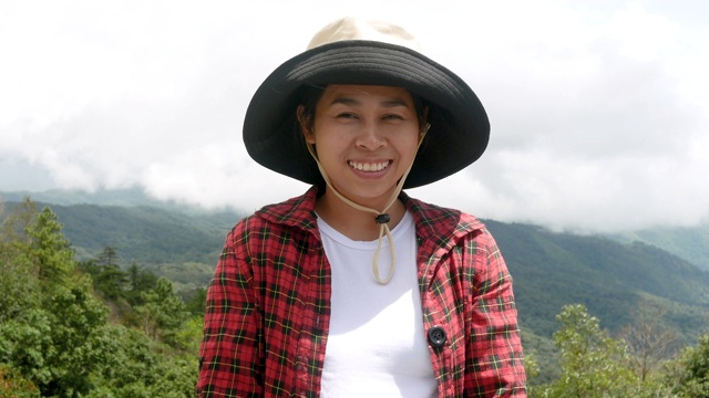 亚洲妇女站在微笑看着相机的自然背景。视频素材