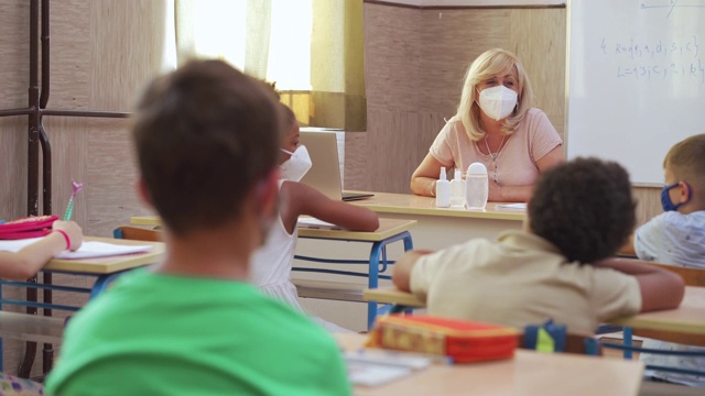 新冠肺炎疫情期间，女教师和学生在教室佩戴防护口罩视频素材