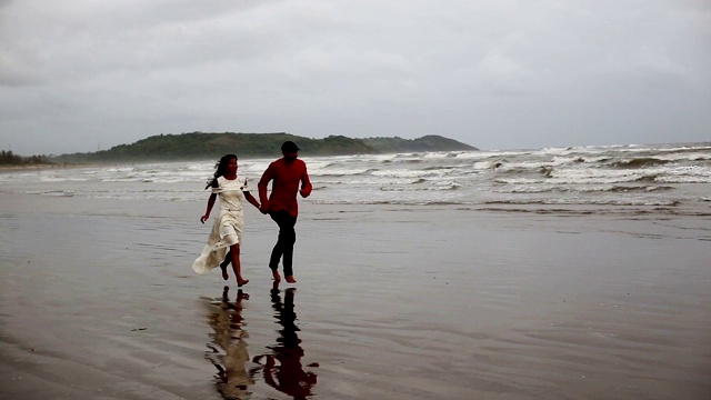 一对情侣在Morjim海滩边独自跑步视频素材
