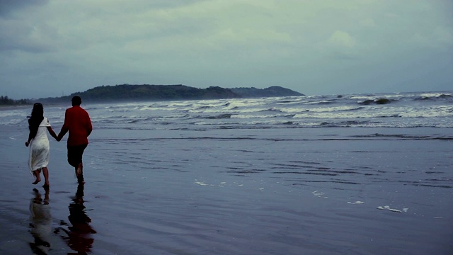一对情侣在Morjim海滩边独自跑步视频素材