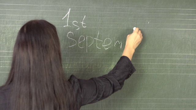 9月1日，年轻的黑发老师用粉笔在黑板上写字。视频下载