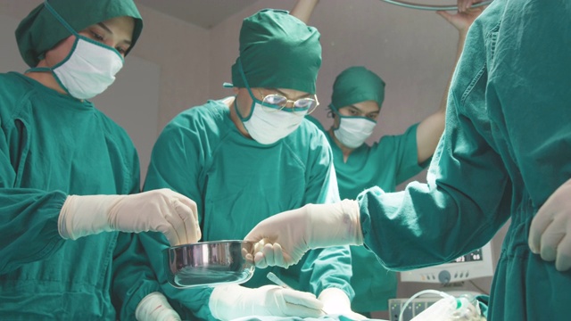 一群亚洲医生、护士和外科医生手中拿着医疗器械，看着病人并做手术。团队合作，医疗保健和医疗理念。外科医生会说话并使用器械。视频素材