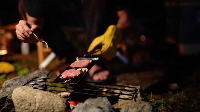 一个人在篝火上烹饪肉的特写镜头视频素材