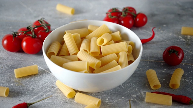 干的意大利面和番茄在碗里慢慢旋转。视频下载