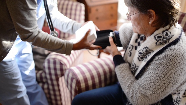 年轻护士在家给一位老年病人量血压视频素材