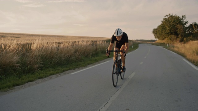 SLO MO职业自行车手在日落时分骑着自行车穿过乡村视频素材